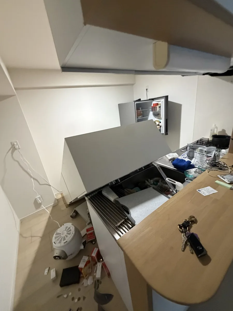 地震直後の自宅キッチンの様子。レンジフードのカバーが外れてシンクに落ち、冷蔵庫の扉が開き、床には食器や日用品が散乱している